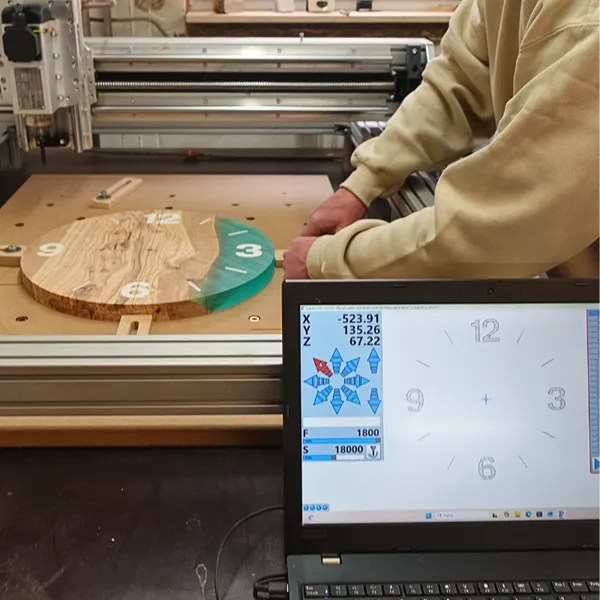 CNC-Fräse bearbeitet eine Wanduhr aus Olivenholz mit Epoxidharz