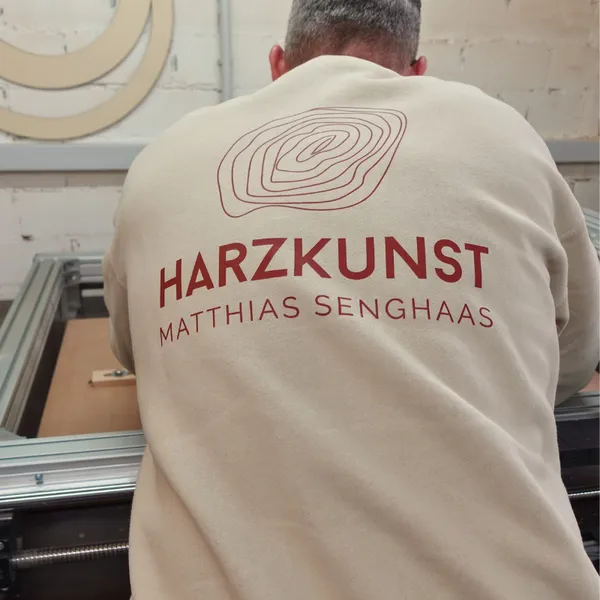 Matthias Senghaas von hinten in der Werkstatt, Pullover mit Harzkunst-Logo